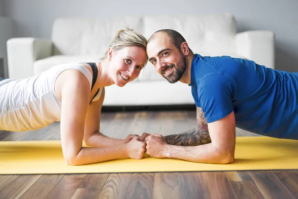 Young couple doing exercise at home in living room. — Stock Photo, Image