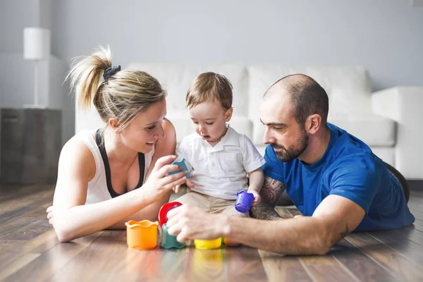 Família feliz com pais e filho brincando com blocos coloridos na sala de estar — Fotografia de Stock