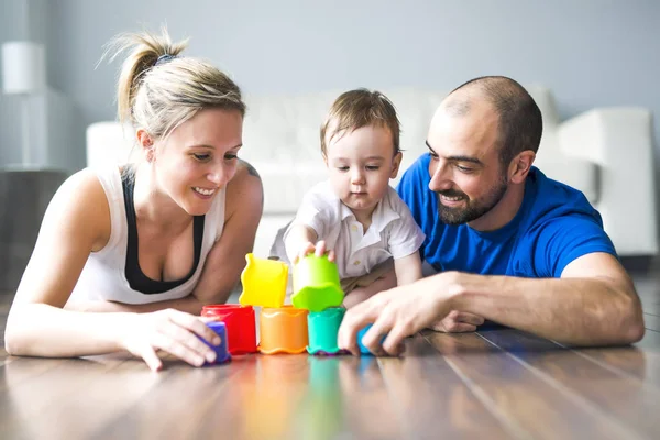 Família feliz com pais e filho brincando com blocos coloridos na sala de estar — Fotografia de Stock