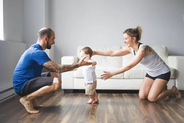 Alegre mamá y papá ayudan a su hijo a caminar en casa —  Fotos de Stock