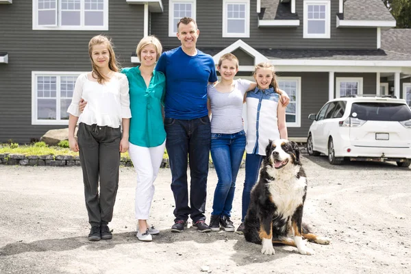 Familia feliz de pie frente a la casa — Foto de Stock