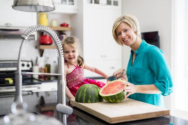 Matka i córka cięte arbuza w kuchni — Zdjęcie stockowe