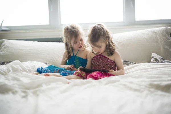 Closeup πορτρέτο των δύο κοριτσιών, ξαπλωμένος στο κρεβάτι και χρησιμοποιώντας tablet — Φωτογραφία Αρχείου