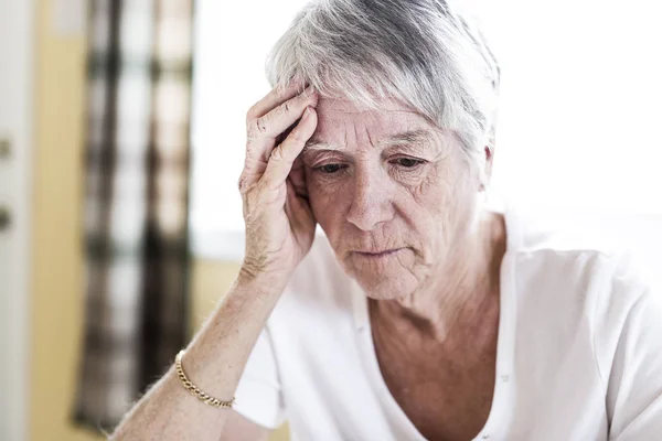 Ώριμη γυναίκα στο σπίτι συγκινητικό το κεφάλι με τα χέρια της, ενώ έχοντας ένα πονοκέφαλο πόνο — Φωτογραφία Αρχείου