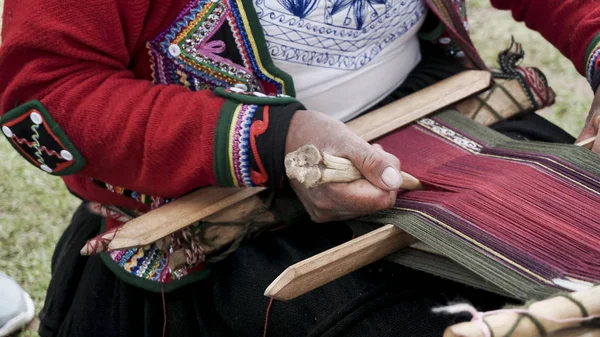 Een Quechuan vrouw demsontrates alpaca wol weven. — Stockfoto