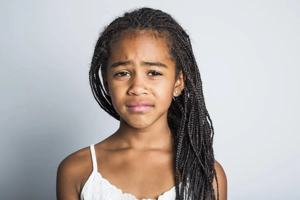 Очаровательная грустная африканская маленькая девочка на сером фоне студии — стоковое фото