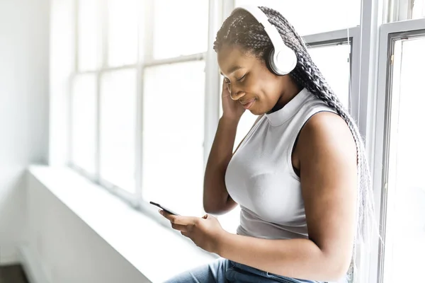 Young teen beautiful African American woman enjoys listening to music with headphones — Stock Photo, Image