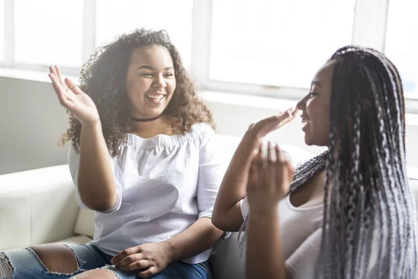 affectionate friends afro american sitting on sofa