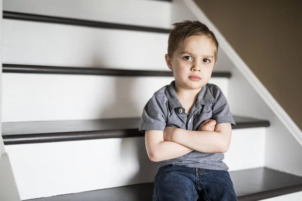 Un niño triste sentado en las escaleras en casa durante el día . — Foto de Stock