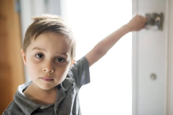 Niño sosteniendo la puerta en casa sonriendo —  Fotos de Stock