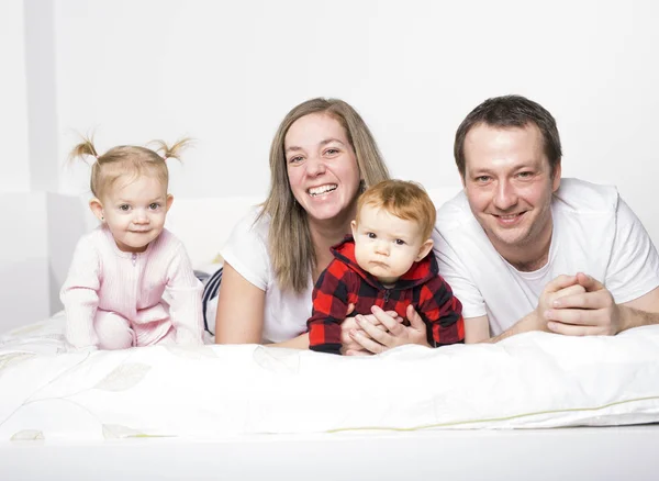 Familj från fyra personer spenderar glatt tid i sängar — Stockfoto