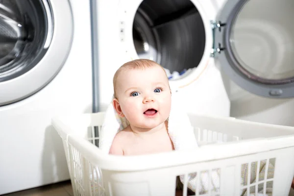 Portrait of an adorable baby sitting in a laundry basket — Stock Photo, Image
