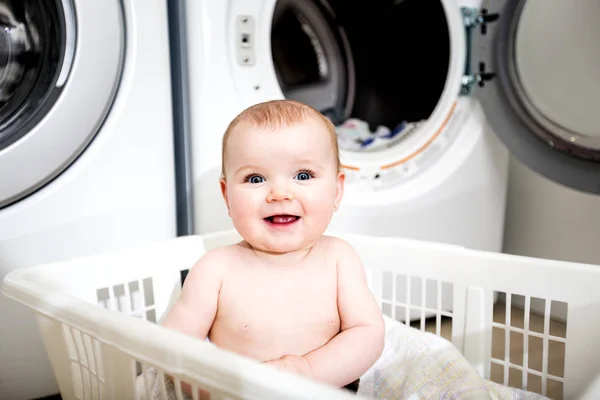 Retrato de un adorable bebé sentado en una canasta de ropa — Foto de Stock