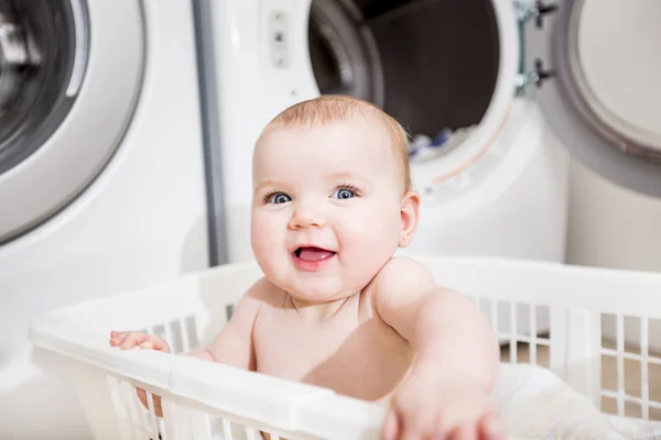 Retrato de un adorable bebé sentado en una canasta de ropa — Foto de Stock