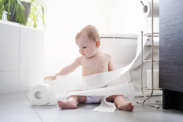 Niño rompiendo papel higiénico en el baño — Foto de Stock