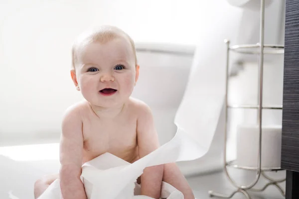 Peuter scheurt wc-papier in de badkamer — Stockfoto