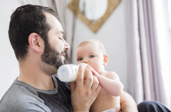 Heureux homme qui donne du lait à bébé fille à la maison — Photo