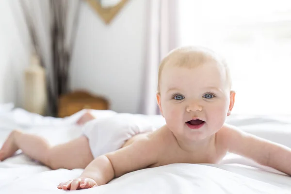 Menina bebê em roupa de cama branca em casa olhar agradável — Fotografia de Stock