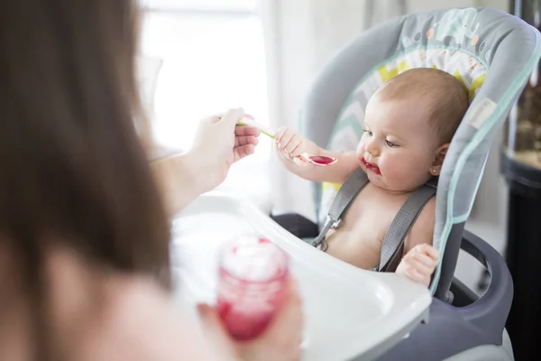 Mère nourrissant bébé fille en chaise haute — Photo