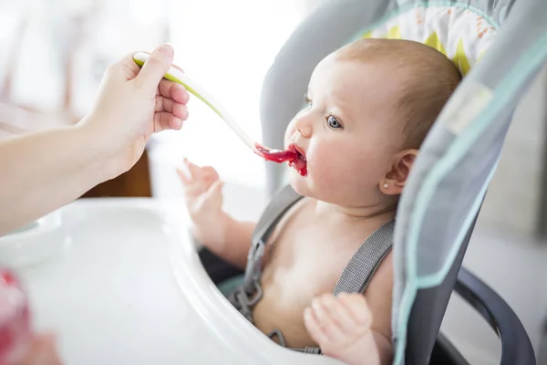 Madre alimentación bebé niña en silla alta — Foto de Stock