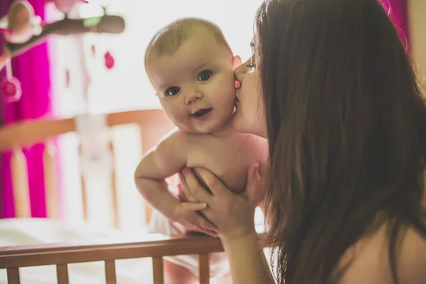 Portrait d'une mère heureuse avec bébé mignon dans la crèche donnant baiser — Photo