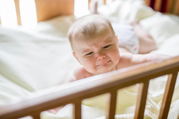 Close-up retrato de um bebê chorando bonito no berço em casa — Fotografia de Stock