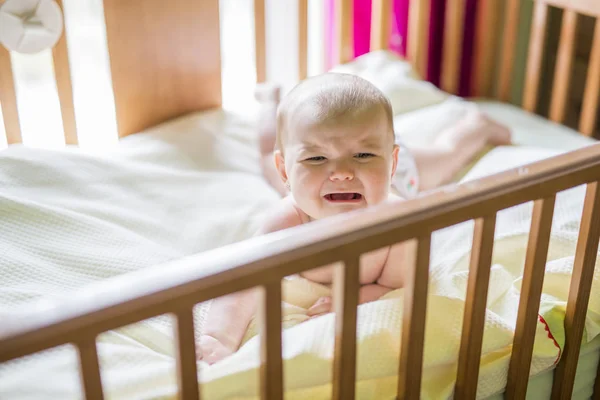 自宅のベビーベッドで泣いているかわいい赤ちゃんのクローズ アップの肖像画 — ストック写真