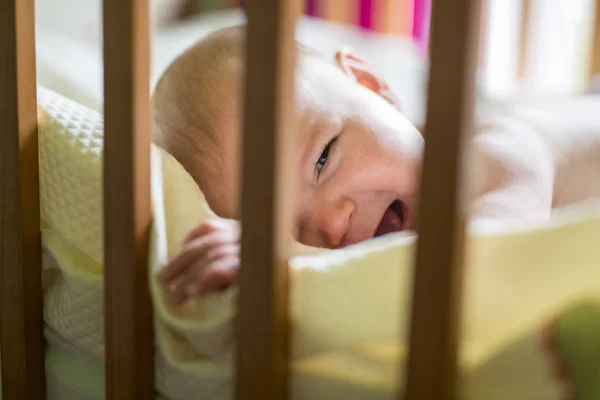 Primo piano ritratto di un bambino carino che piange nella culla a casa — Foto Stock