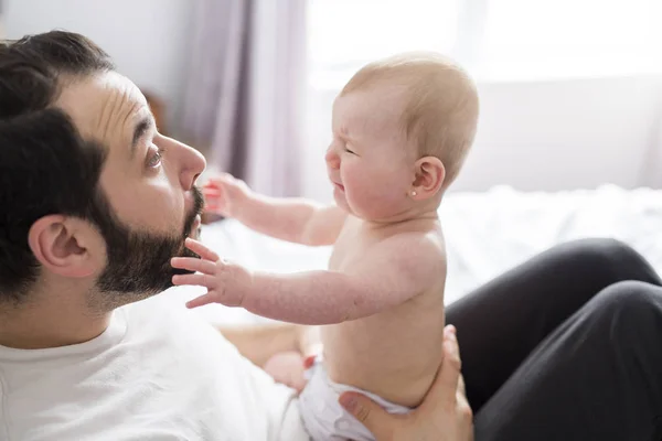 Joven padre feliz jugando con cama de bebé — Foto de Stock