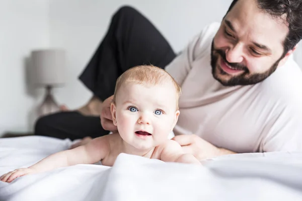 Young happy father playing with babyon bed — Stock Photo, Image