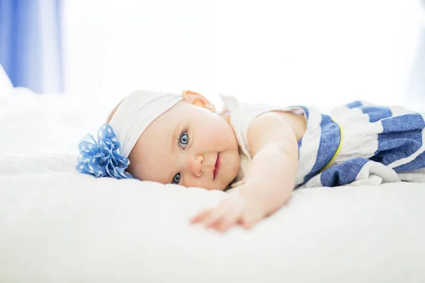 Menina bebê em roupa de cama branca em casa olhar agradável — Fotografia de Stock