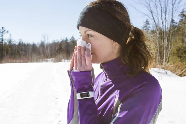 Runner kobieta dmuchanie nosa poza na zimno — Zdjęcie stockowe