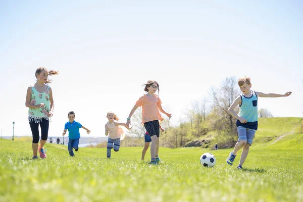Мальчики и девочки бегут к футболу — стоковое фото