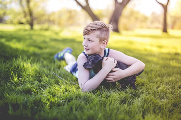 Ładny, młody chłopak w ogrodzie gospodarstwa pies bokser — Zdjęcie stockowe