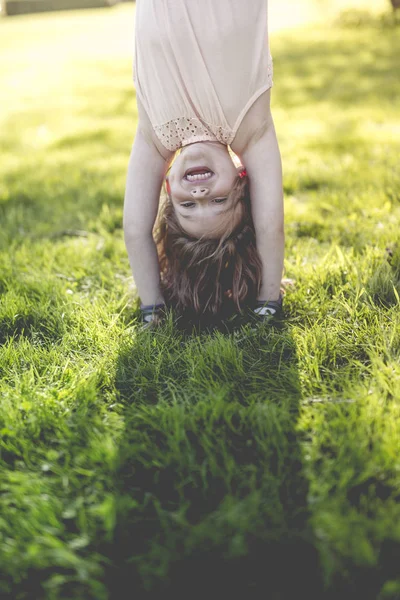 Criança feliz brincando na grama verde ao ar livre no parque da primavera — Fotografia de Stock