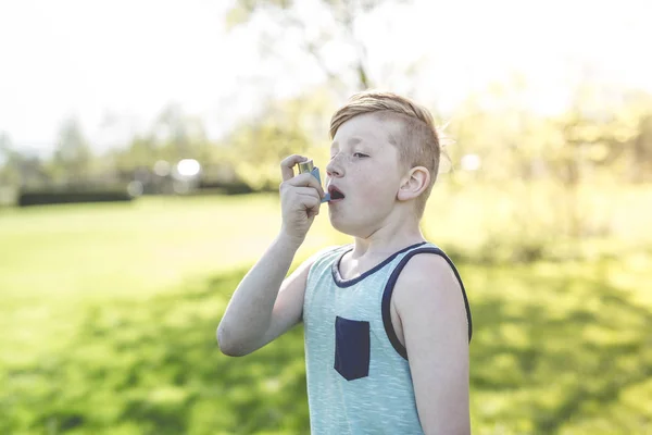 Niño usando un inhalador de asma en el parque —  Fotos de Stock