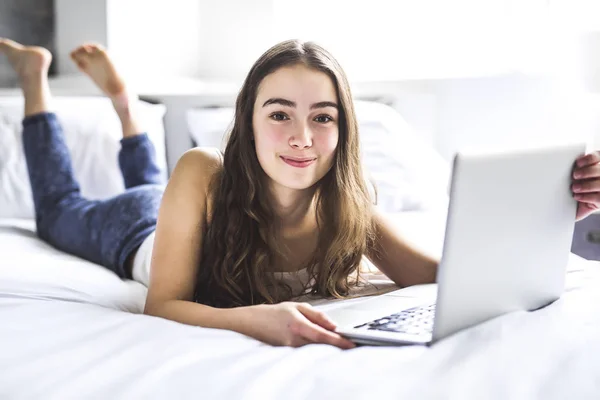 Дівчина лежить на ліжку використовуючи ноутбук — стокове фото