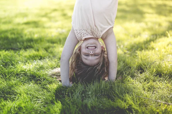 Счастливый ребенок играет на зеленой траве в весеннем парке — стоковое фото