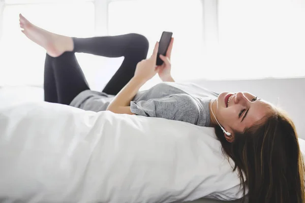 Mujer feliz o adolescente con auriculares escuchando música desde un teléfono inteligente —  Fotos de Stock