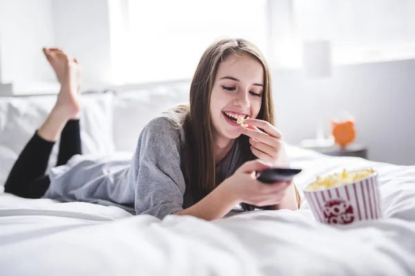 Giovane adolescente guardando film a letto con popcorn — Foto Stock