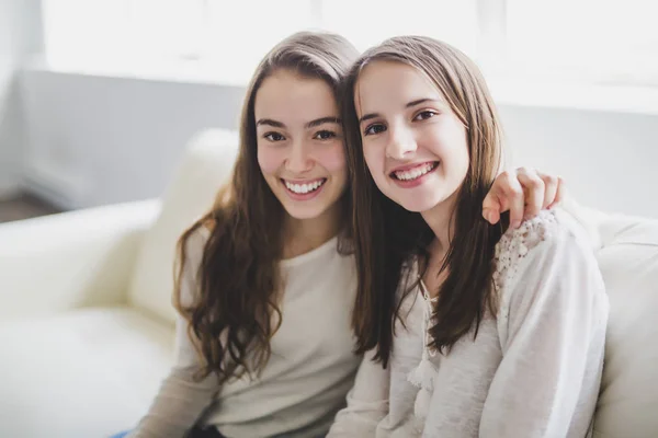 Primer plano retrato de abrazar a 2 hermosas mujeres jóvenes divirtiéndose en el sofá —  Fotos de Stock