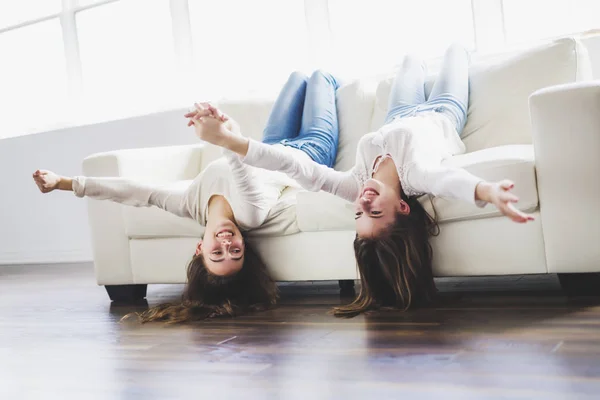 Primer plano retrato de abrazar a 2 hermosas mujeres jóvenes divirtiéndose en el sofá —  Fotos de Stock