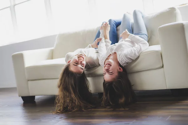 Портрет крупным планом, на котором обнимаются две красивые девушки, веселящиеся на диване — стоковое фото
