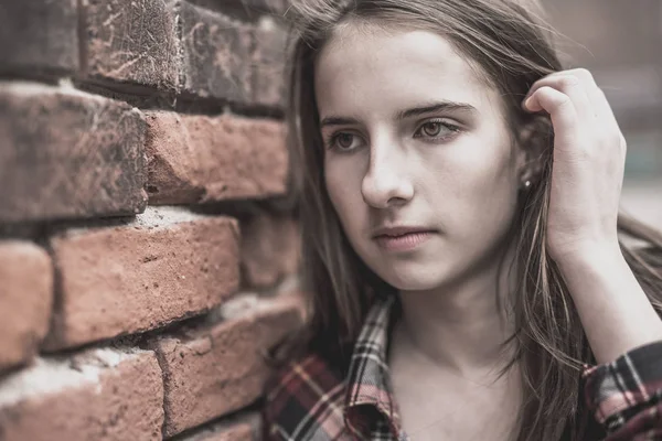 Adolescente chica contra una pared de ladrillo — Foto de Stock