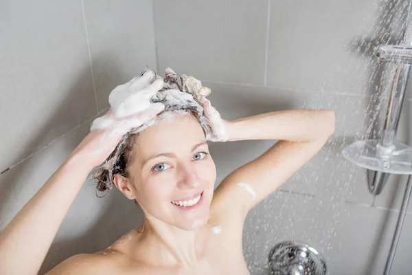 Mulher no chuveiro lavar o cabelo com shampoo — Fotografia de Stock