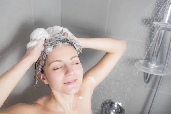 Mulher no chuveiro lavar o cabelo com shampoo — Fotografia de Stock