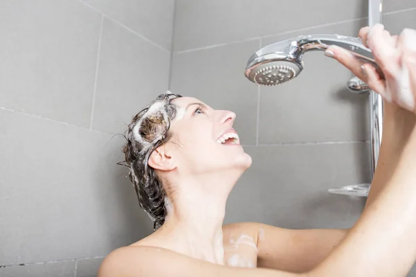 Жінка в душі миє волосся з шампунем — стокове фото
