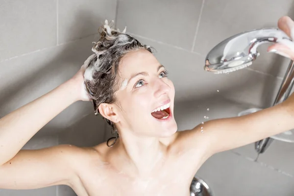 Жінка в душі миє волосся з шампунем — стокове фото