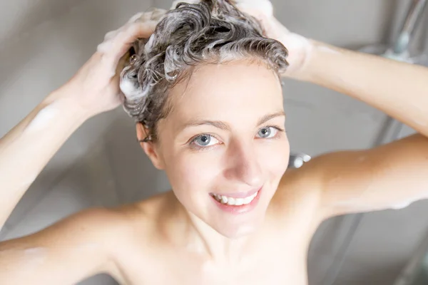 Mulher no chuveiro lavar o cabelo com shampoo — Fotografia de Stock