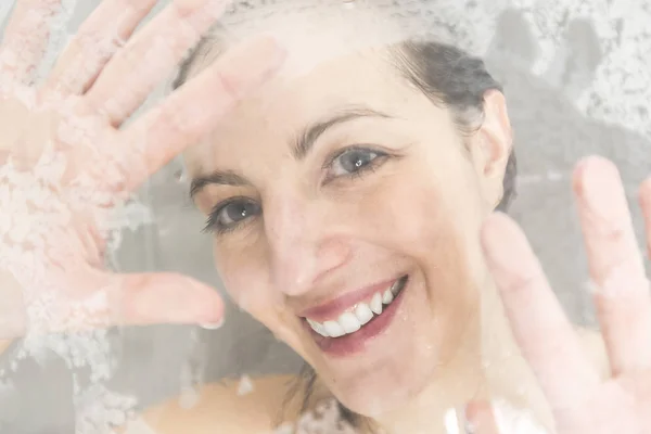 Retrato de cerca de una mujer divirtiéndose tocando el vidrio en la ducha — Foto de Stock
